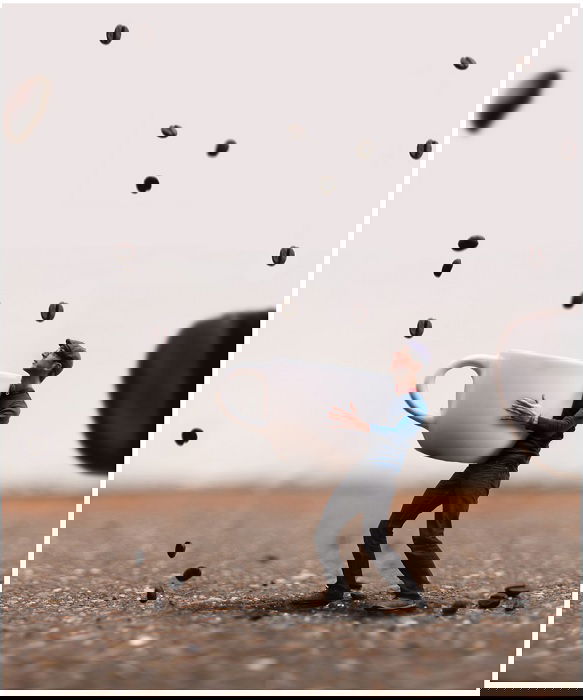 miniature scene of a man catching coffee beans with a cup as a creative Photoshop idea