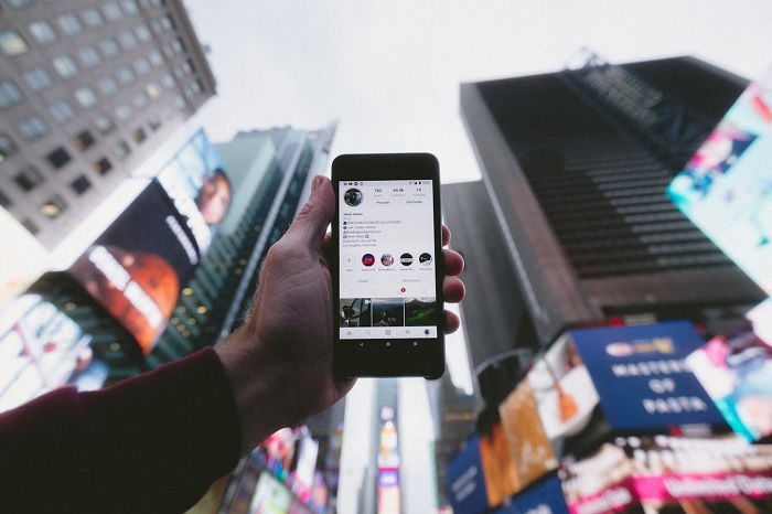 Hand holding a smartphone with Instagram on it in a city